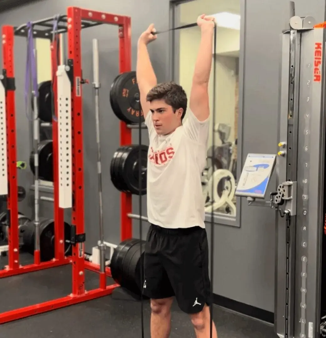 Man exercising with resistance band in gym.