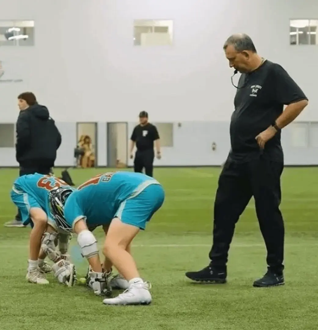 Coach observing players practicing indoor lacrosse.