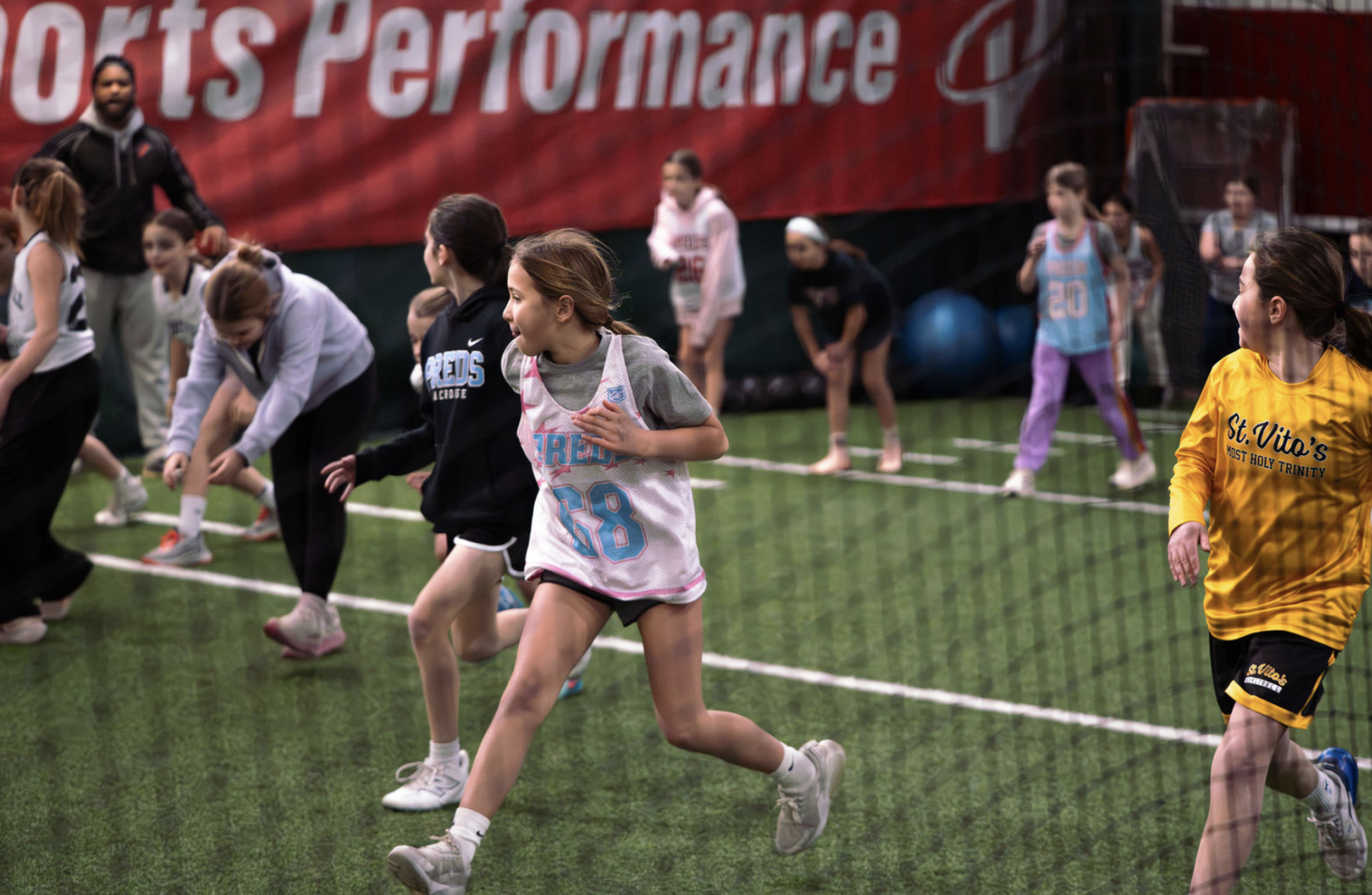 Kids playing sports indoors on artificial turf.