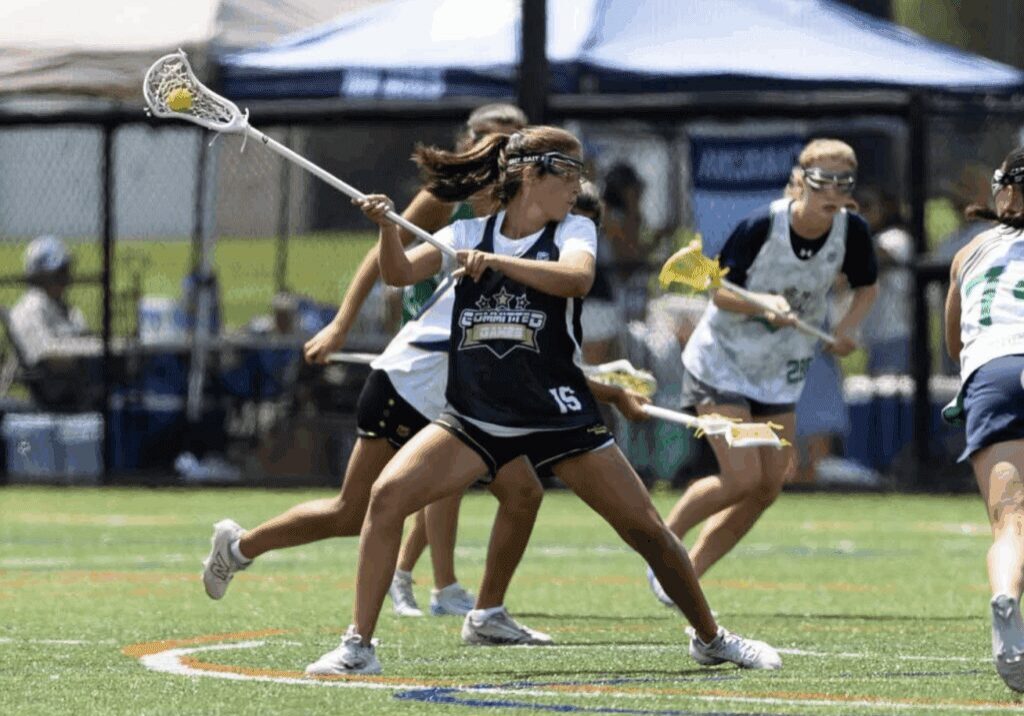 Girls playing lacrosse on a sunny field..