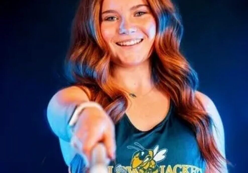 Smiling athlete holding a lacrosse stick.