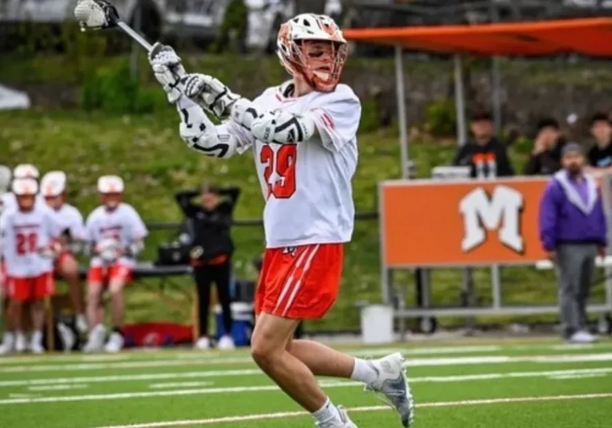 Lacrosse player in white and red uniform preparing to throw the ball.