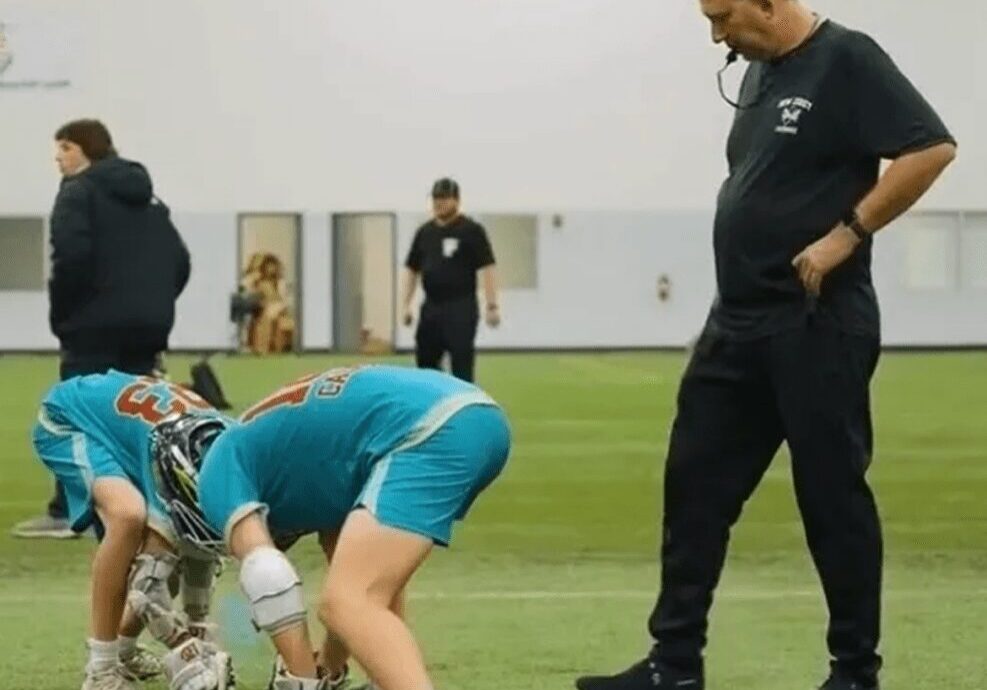 Coach observing players practicing indoor lacrosse.