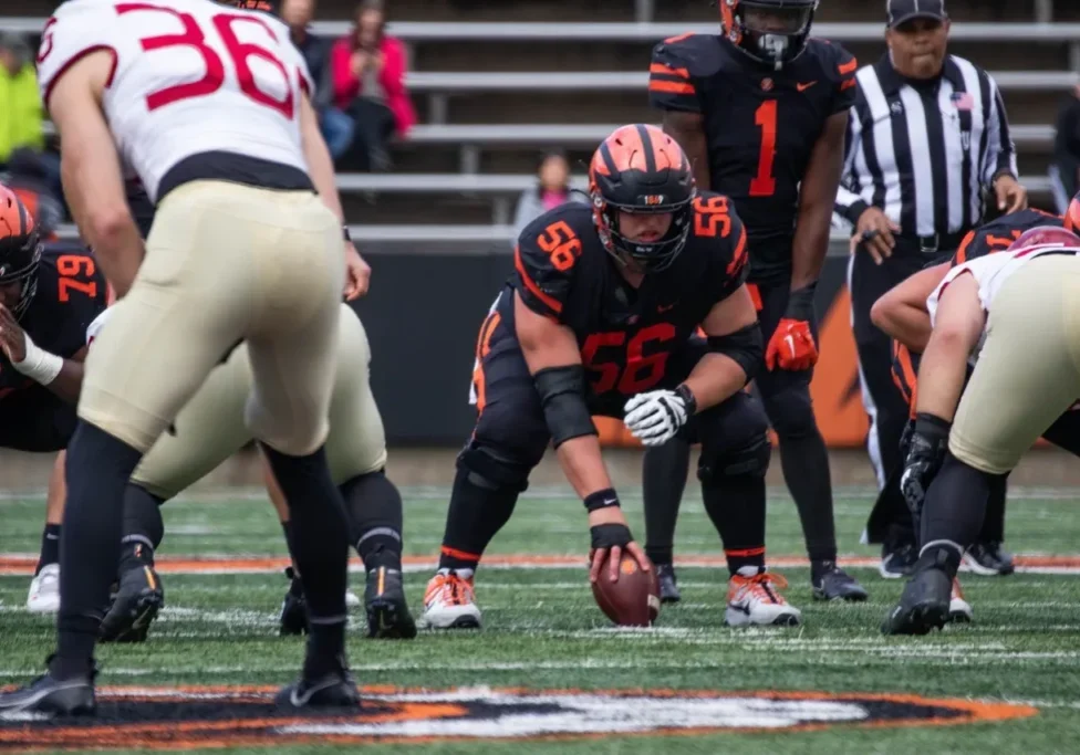 Football player in black and orange uniform preparing to snap the ball.